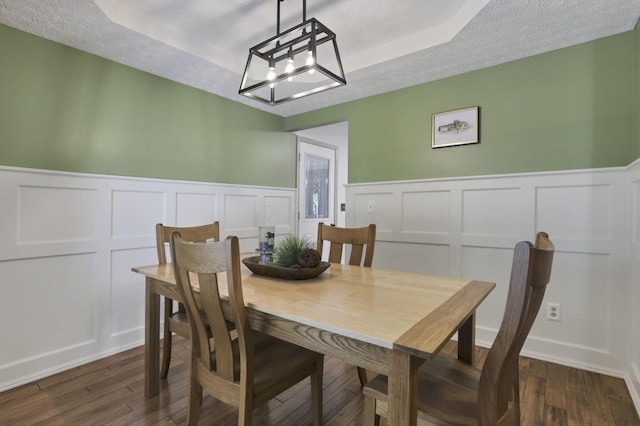 215 Barb Ct, Heath, OH 43056 - dining area with a tray ceiling, a decorative wall, a chandelier, dark wood-style flooring, and wainscoting