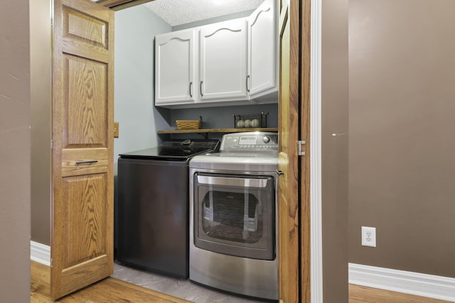 215 Barb Ct, Heath, OH 43056 - laundry area with washing machine and clothes dryer, cabinet space, light wood-style floors, and a textured ceiling