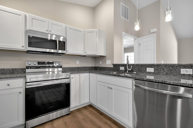 752 Whitetail Lp, Newark, OH 43055 - kitchen featuring appliances with stainless steel finishes, dark wood finished floors, white cabinetry, decorative light fixtures, and dark stone countertops