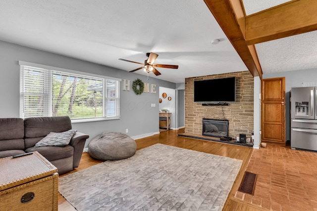 890 Elm Dr, Columbus, OH 43235 - living area featuring a ceiling fan, a fireplace, a textured ceiling, and light wood-style floors
