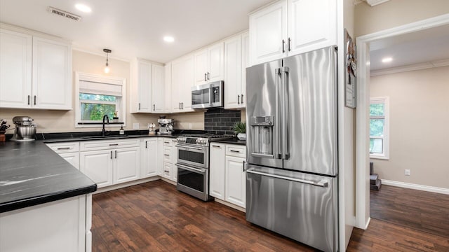 2830 Silver St, Granville, OH 43023 - kitchen with appliances with stainless steel finishes, dark countertops, white cabinetry, dark wood-style floors, and ornamental molding