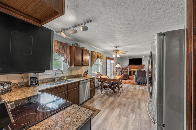 5681 Mcbride Ct, Dublin, OH 43016 - kitchen with appliances with stainless steel finishes, ceiling fan, a fireplace, a textured ceiling, and light wood finished floors