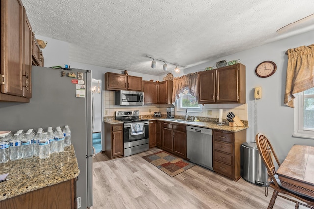 5681 Mcbride Ct, Dublin, OH 43016 - kitchen featuring appliances with stainless steel finishes, light wood-style floors, plenty of natural light, a textured ceiling, and light stone countertops