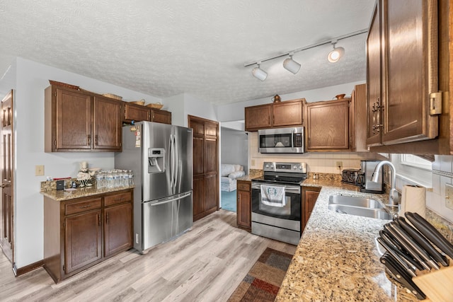 5681 Mcbride Ct, Dublin, OH 43016 - kitchen featuring appliances with stainless steel finishes, light wood-type flooring, light stone counters, and a textured ceiling