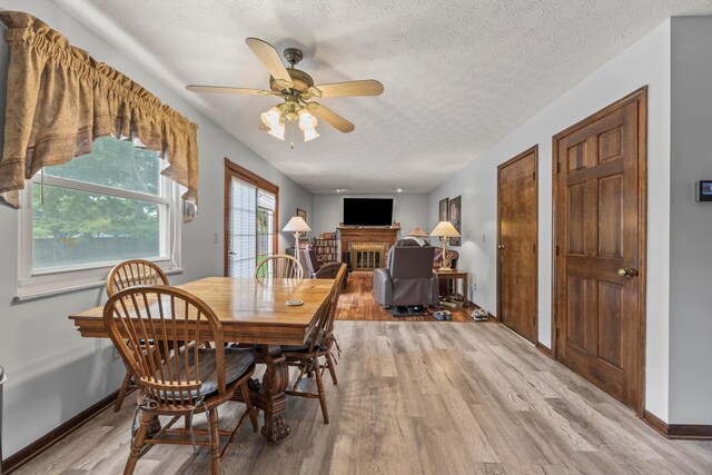 5681 Mcbride Ct, Dublin, OH 43016 - dining room with light wood-type flooring, a fireplace, a textured ceiling, and a ceiling fan