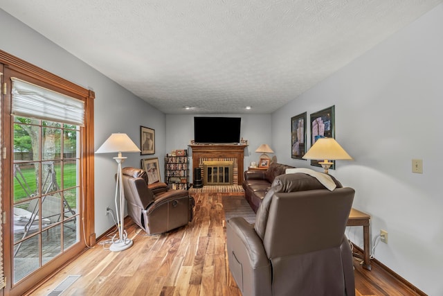 5681 Mcbride Ct, Dublin, OH 43016 - living room with a textured ceiling, light wood-style flooring, and a brick fireplace