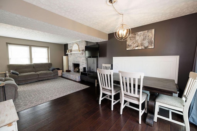 3790 Hunting Ln, Columbus, OH 43230 - dining area featuring a textured ceiling, dark wood-type flooring, a fireplace, and a chandelier
