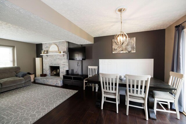 3790 Hunting Ln, Columbus, OH 43230 - dining space featuring wood-type flooring, a textured ceiling, a chandelier, and a brick fireplace