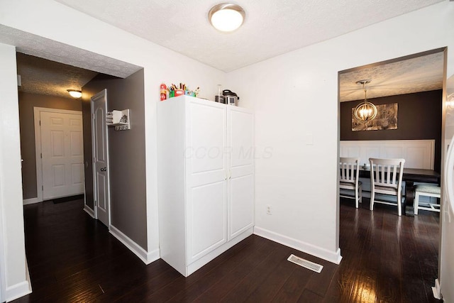 3790 Hunting Ln, Columbus, OH 43230 - hallway featuring dark wood-type flooring, a chandelier, and a textured ceiling