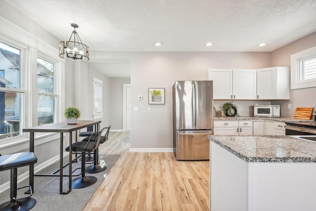 743 Reinhard Ave, Columbus, OH 43206 - kitchen featuring stainless steel appliances, light wood finished floors, white cabinetry, light stone countertops, and a chandelier