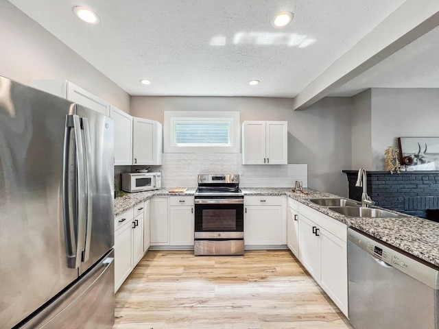 743 Reinhard Ave, Columbus, OH 43206 - kitchen featuring appliances with stainless steel finishes, tasteful backsplash, white cabinetry, light wood-style flooring, and a textured ceiling