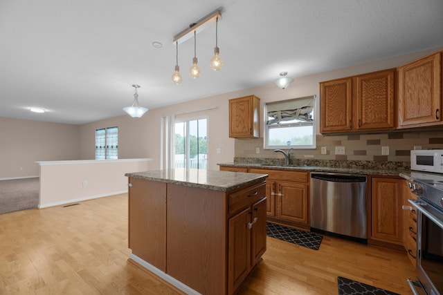 8101 Orange Station Loop, Lewis Center, OH 43035 - kitchen with appliances with stainless steel finishes, a kitchen island, brown cabinetry, light wood-style flooring, and decorative light fixtures