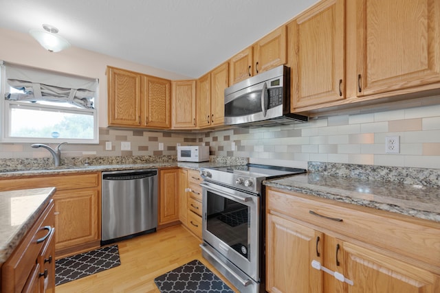 8101 Orange Station Loop, Lewis Center, OH 43035 - kitchen with appliances with stainless steel finishes, light wood finished floors, tasteful backsplash, and light stone counters