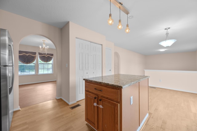 8101 Orange Station Loop, Lewis Center, OH 43035 - kitchen with arched walkways, freestanding refrigerator, brown cabinetry, a chandelier, and light wood finished floors