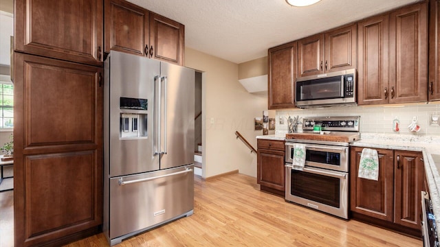 637 Livingston Ct, Heath, OH 43056 - kitchen featuring appliances with stainless steel finishes, tasteful backsplash, light wood-style floors, light stone countertops, and a textured ceiling