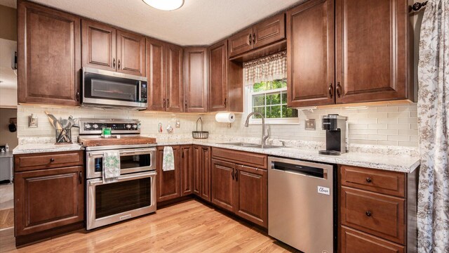 637 Livingston Ct, Heath, OH 43056 - kitchen with stainless steel appliances, light wood-style flooring, decorative backsplash, and light stone counters