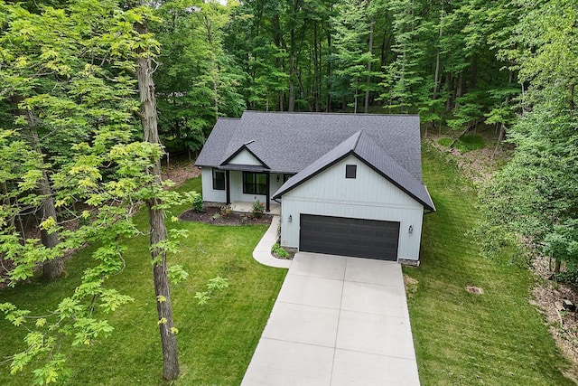 2499 Apple Valley Dr, Howard, OH 43028 - modern inspired farmhouse featuring a front lawn, roof with shingles, concrete driveway, a garage, and a wooded view