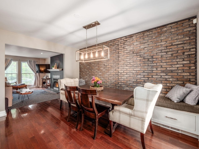 1243 Harrison Ave, Columbus, OH 43201 - dining room with brick wall, hardwood / wood-style floors, and a lit fireplace