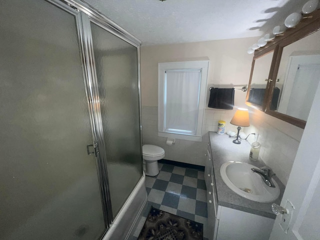 85 Landers Ave, Columbus, OH 43207 - bathroom featuring tile walls, vanity, tile patterned floors, a wainscoted wall, and shower / bath combination with glass door