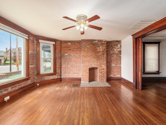 1360 S High St, Columbus, OH 43207 - unfurnished living room featuring wood finished floors, a ceiling fan, brick wall, and a brick fireplace