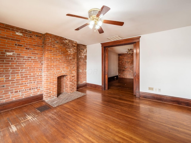 1360 S High St, Columbus, OH 43207 - unfurnished living room featuring wood finished floors, a fireplace, a ceiling fan, and brick wall