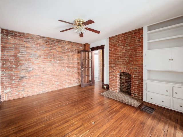 1360 S High St, Columbus, OH 43207 - unfurnished living room featuring hardwood / wood-style floors, ceiling fan, built in shelves, a brick fireplace, and brick wall