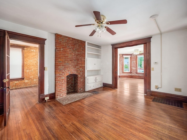 1360 S High St, Columbus, OH 43207 - unfurnished living room featuring a brick fireplace, hardwood / wood-style flooring, built in shelves, and ceiling fan
