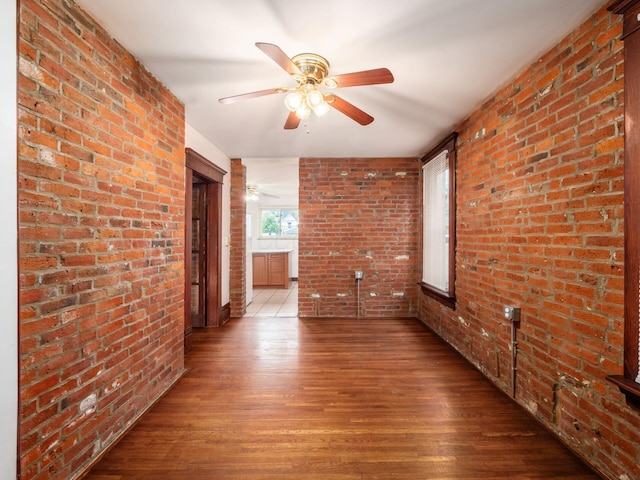 1360 S High St, Columbus, OH 43207 - unfurnished living room featuring brick wall, wood finished floors, and a ceiling fan