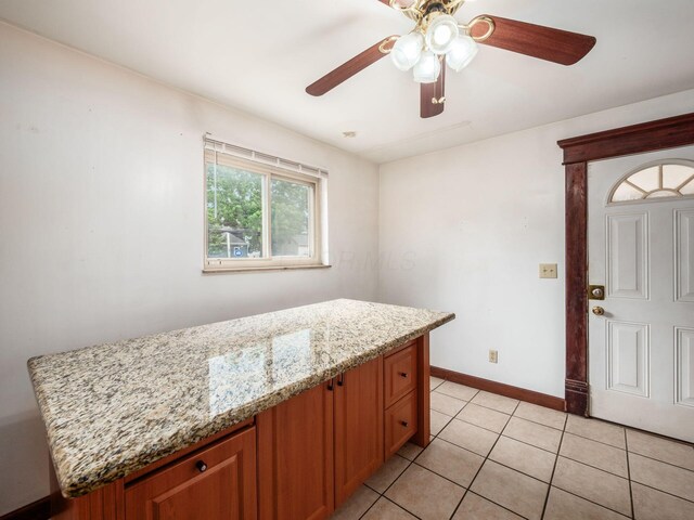 1360 S High St, Columbus, OH 43207 - kitchen featuring light stone countertops, light tile patterned flooring, a ceiling fan, and brown cabinets