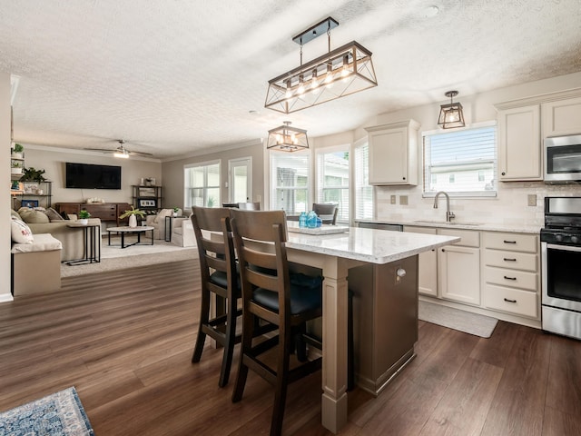 3538 Rosburg Dr, Columbus, OH 43228 - kitchen featuring appliances with stainless steel finishes, a textured ceiling, dark wood-style flooring, light stone counters, and a kitchen island