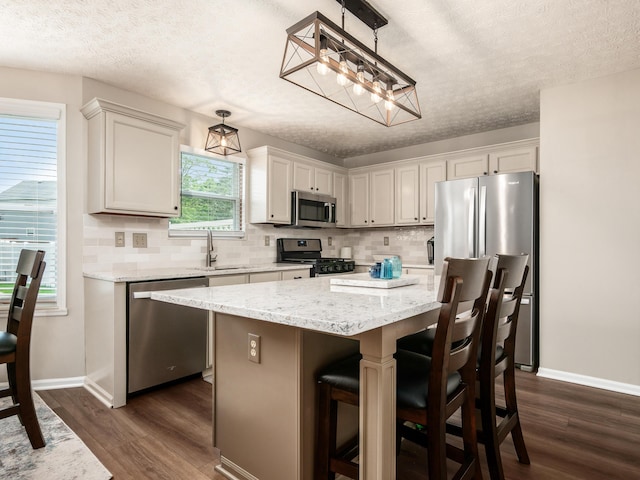 3538 Rosburg Dr, Columbus, OH 43228 - kitchen with stainless steel appliances, a textured ceiling, dark wood-type flooring, backsplash, and a kitchen island