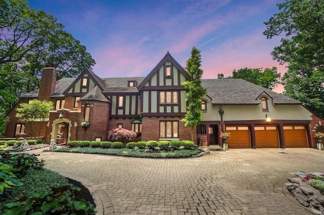 2475 Signal Hill Rd, Springfield, OH 45504 - tudor home with stucco siding, a chimney, decorative driveway, brick siding, and a garage