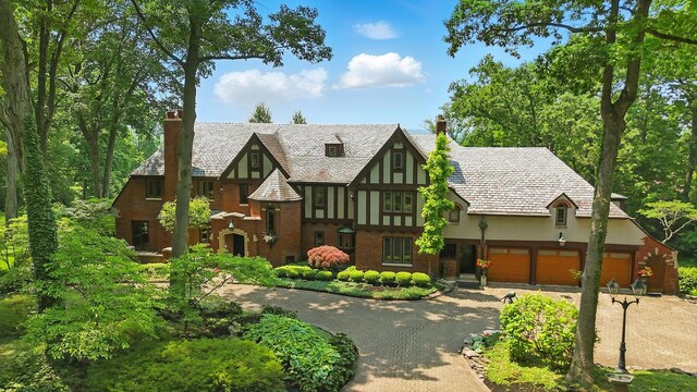 2475 Signal Hill Rd, Springfield, OH 45504 - tudor home featuring driveway, a chimney, a garage, stucco siding, and brick siding