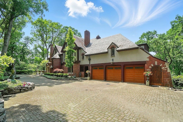 2475 Signal Hill Rd, Springfield, OH 45504 - view of side of home featuring an attached garage, decorative driveway, a chimney, and brick siding