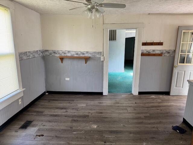2841 E 10th Ave, Columbus, OH 43219 - empty room featuring a ceiling fan, dark wood-style flooring, a textured ceiling, and wainscoting