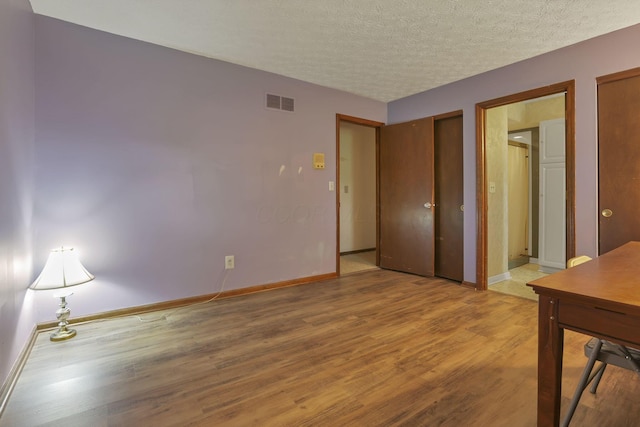 2809 Bella Via Ave, Columbus, OH 43231 - unfurnished bedroom with light wood-type flooring, multiple closets, and a textured ceiling