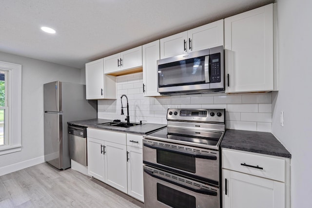 1430 Aberdeen Ave, Columbus, OH 43211 - kitchen featuring appliances with stainless steel finishes, dark countertops, light wood finished floors, tasteful backsplash, and recessed lighting