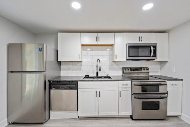 1430 Aberdeen Ave, Columbus, OH 43211 - kitchen with stainless steel appliances, dark countertops, white cabinets, tasteful backsplash, and light wood finished floors