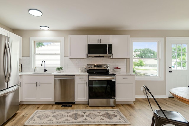 99 Ramona Ave, Newark, OH 43055 - kitchen with appliances with stainless steel finishes, light countertops, light wood finished floors, decorative backsplash, and white cabinets