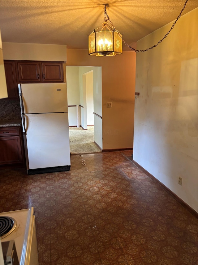 54 Appleview Ct, Howard, OH 43028 - kitchen featuring freestanding refrigerator, a chandelier, pendant lighting, dark flooring, and dark brown cabinetry