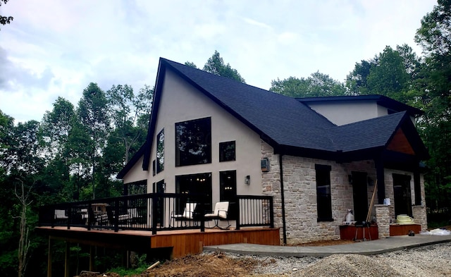 18358 Buckingham Rd, Logan, OH 43138 - view of front facade with stone siding, a shingled roof, stucco siding, and a wooden deck