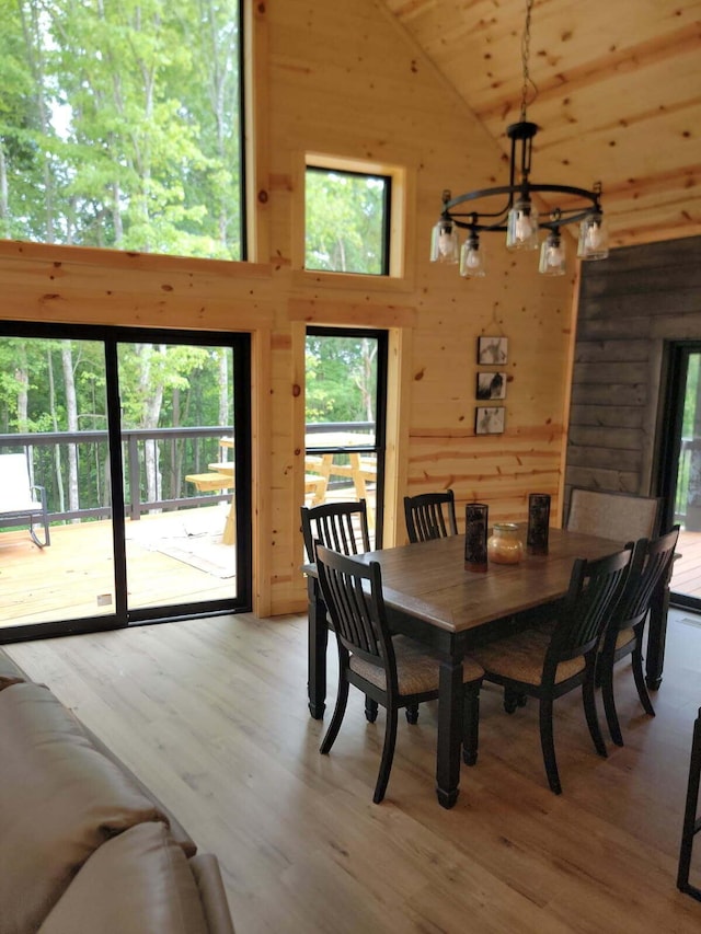 18358 Buckingham Rd, Logan, OH 43138 - dining space featuring a chandelier, high vaulted ceiling, wooden walls, plenty of natural light, and light wood-type flooring