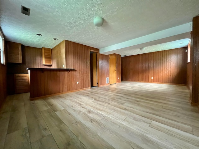 5200 Williamsburg Cir, Hilliard, OH 43026 - unfurnished living room featuring light wood-type flooring, wood walls, and a textured ceiling