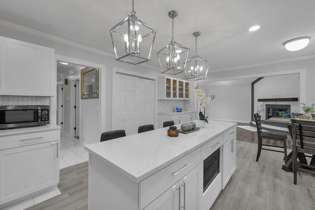 7732 Quarry Cliff Ct, Reynoldsburg, OH 43068 - kitchen featuring stainless steel microwave, built in microwave, ornamental molding, a chandelier, and white cabinetry