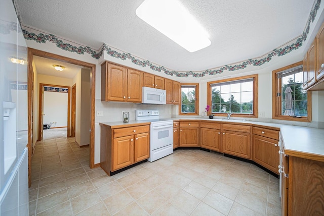 1948 Wendover Cir NE, North Canton, OH 44720 - kitchen with white appliances, a textured ceiling, light countertops, brown cabinets, and light tile patterned flooring