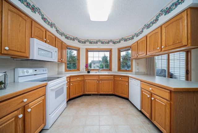 1948 Wendover Cir NE, North Canton, OH 44720 - kitchen featuring white appliances, a textured ceiling, a peninsula, light countertops, and brown cabinets