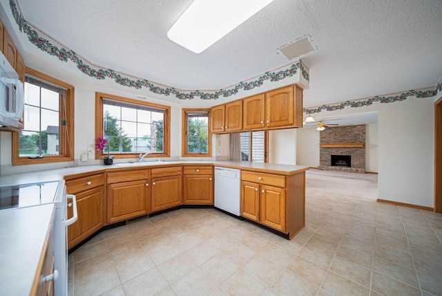 1948 Wendover Cir NE, North Canton, OH 44720 - kitchen with white appliances, a textured ceiling, a peninsula, light countertops, and a large fireplace