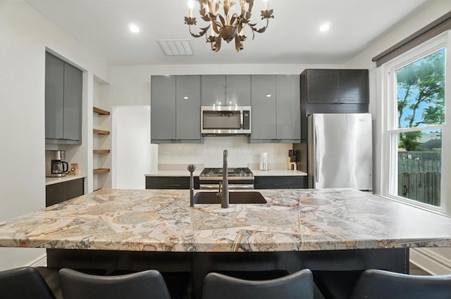 626 S 22nd St, Columbus, OH 43205 - kitchen featuring stainless steel appliances, gray cabinets, a chandelier, light countertops, and a kitchen bar