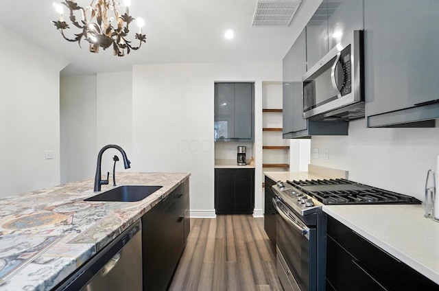 626 S 22nd St, Columbus, OH 43205 - kitchen with appliances with stainless steel finishes, dark wood-style floors, light countertops, a chandelier, and dark cabinetry