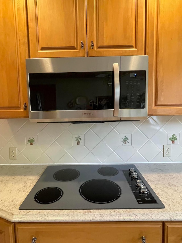 2666 Eugene Ave, Grove City, OH 43123 - kitchen view of electric cooktop, stainless steel microwave, brown cabinetry, and decorative backsplash